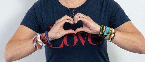 Hands making a heart wearing beaded bracelets